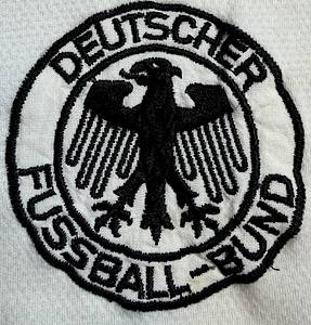 DFB - Trikot 1986 WM  | Für das WM-Finale 1986 in Mexiko Deutschland gegen Argentinien wurde dieses besondere Trikot ursprünglich für Matthias Herget vorbereitet. Das Shirt basiert auf dem seltenen weißen adidas-Design im Stil des damaligen Trainingsoberteils.ach damaliger Entscheidung der FIFA kam dieses Trikot im Finale jedoch nicht zum Einsatz. Da Argentinien als Heimteam geführt wurde, galt die Farbkombination des weißen deutschen Trikots im Zusammenspiel mit den hellblauen argentinischen Streifen als zu ähnlich. Um mögliche Verwechslungen zu vermeiden, lief das DFB -Team deshalb erneut im grünen Auswärtstrikot aus dem Vorrundenspiel gegen Uruguay auf. Trikot kommt aus der Sammlung vom deutschen Nationalspieler Matthias Herget Status AAA,. - Bild 4