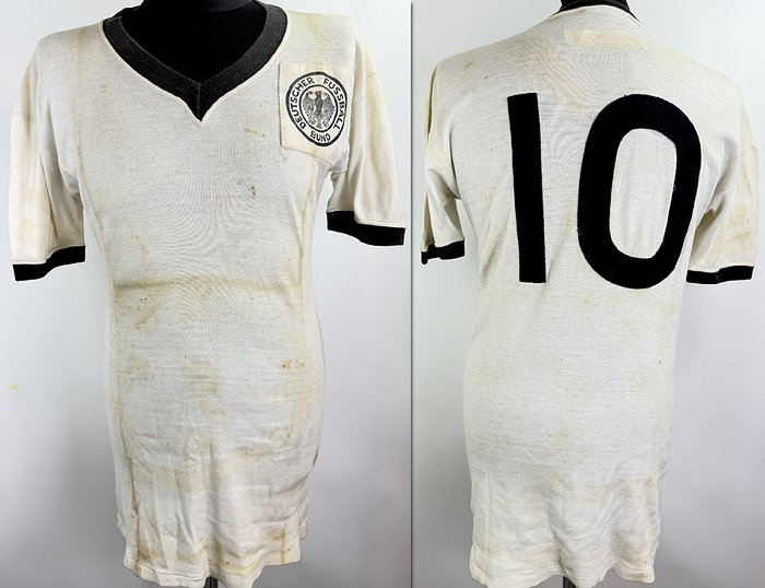  - Original match-worn DFB (German Football Association) player shirt with the number 10, worn by Günter Netzer. Worn in the international match against Brazil on December 14, 1968, in Rio de Janeiro. Manufacturer: Umbro. Comes from the collection of a former DFB employee. Condition: AAB (Grade AAB). Short-sleeved shirt; size M; DFB logo stitched on, number sewn on in linen; minor signs of storage; jersey shows signs of wear and storage; 100% cotton; Made in England; Condition: B