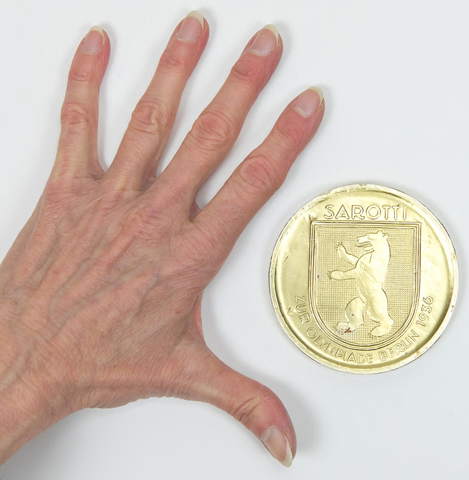 Schokoladenmünze OSS1936  | Original Schokoladentaler des Schokoladenherstellers "Sarotti" für die Olympischen Spiele Berlin 1936 mit der Inschrift "Sarotti - Zur Olympiade Berlin 1936". Goldenes Aluminiumpapier, Dicke: 0,4 cm. Durchmesser: 8,2 cm.
