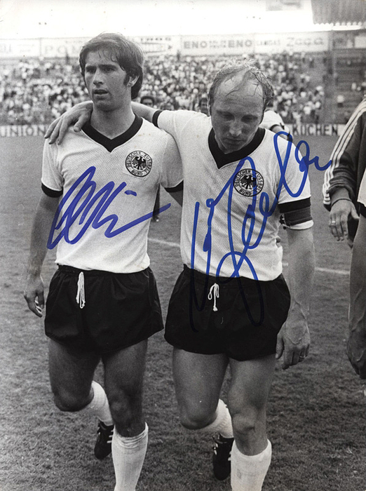 Müller,Gerd / Seeler, Uwe  | S/W-Pressefoto (Nordbild) mit den Originalsignaturen von Gerd Müller (1945-2012) und Uwe Seeler (1936-2022; Vizeweltmeister 1966, WM-Dritter 1970, 72 A-LS 1954–1970) bei der Fußball-Weltmeisterschaft 1970. 21x16 cm.