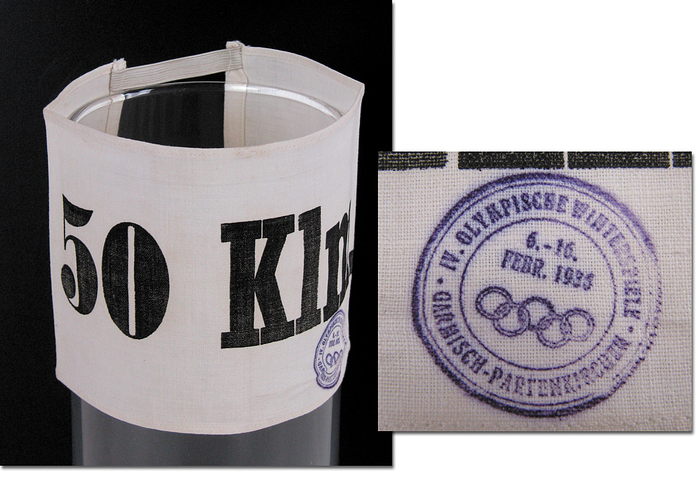 Olympic Games 1936 Skiing: Official Bib - Official Cross Country Skier's bib from the Olympic Winter  Games 1936. With original Olympic 1936 stamp,  white cloth, with  black lettering " 50Km." and original bands. Size 16.5x11.5cm. EF. Condition: A