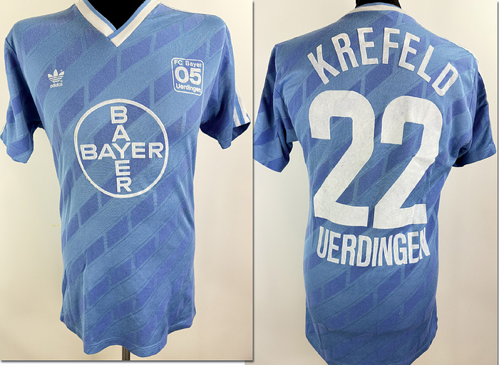  - Original match-worn Bayer 05 Uerdingen player's shirt (number 22, worn by a substitute) from the 1987/1988 season. The shirt comes from the collection of Matthias Herget. Status:ABA. short-sleeved shirt; size 7/8 (L); flocked Bayer 05 crest; rubberized manufacturer logo; back number and chest sponsor applied using the wet-flock process; 41% cotton, 49% polyester; made in Yugoslavia. Condition: A