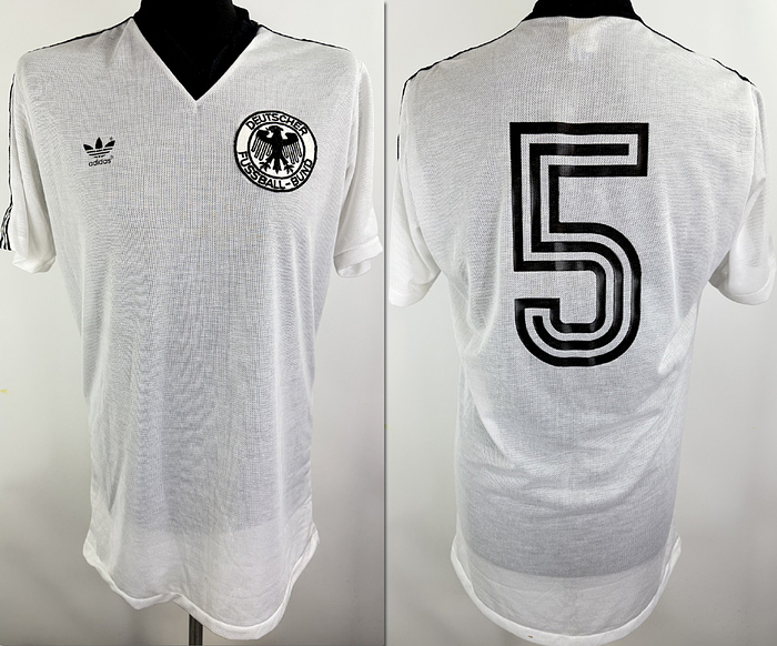 DFB - Trikot 1985  | Original match worn DFB Spielertrikot der mit der Nummer 5 von Matthias Herget, getragen im Spiel gegen England am 12.06.1985 in Mexiko-Stadt. Hierbei handelt es sich um ein sehr besonders seltenes Trikot der deutschen Nationalmannschaft. Im Hinblick auf die hohen Temperaturen bei der Weltmeisterschaft 1986 in Mexiko wurde bei diesem Spiel bereits eine neue, besonders luftdurchlässige Stoffvariante im sogenannten Airtex-Stil getestet. Diese Ausführung wurde von der deutschen Nationalmannschaft nur bei diesem einen Spiel getragen und ist entsprechend selten. Trikot. Kommt aus der Sammlung von Matthias Herget. Status AAA