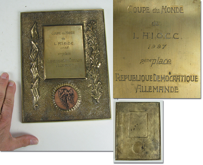 Cycling World Championships 1987. Winner Plaque - Large and heavy trophy of merit of the AIOCC (Association International des Organisateur des Courses Cyclistes) for the race cycling team of the GDR that ranked second in the amateurs list. Inscribed "Coupe du Monde de l'A.I.O.C.C. 1987 - 2ième place Republique Democratique Allemande". Gilt bronze with mounted bronze plaque showing cyclists. 25 x 19.5 cm Condition: A-