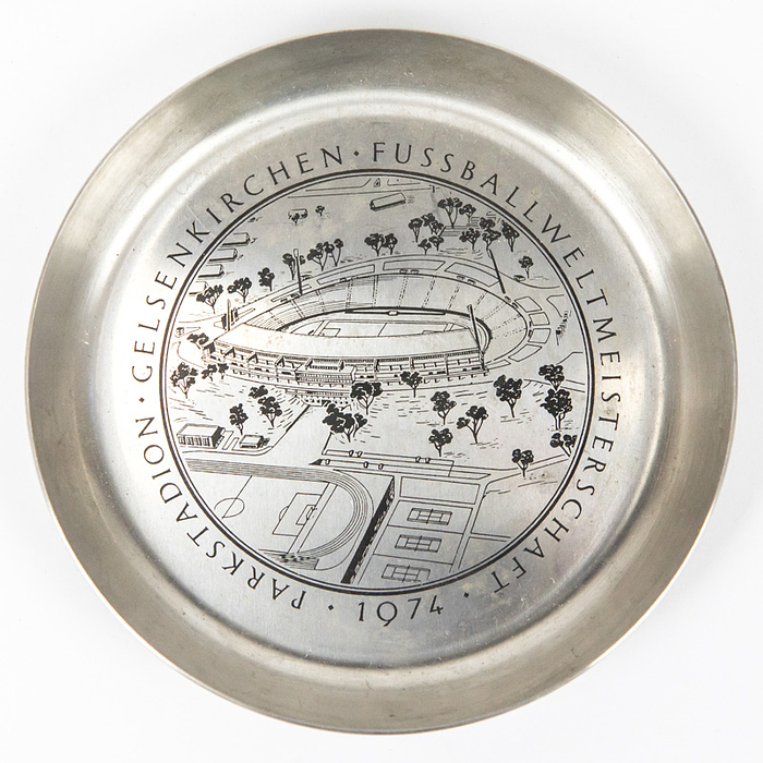 Erinnerungsteller WM 1974  | Erinnerungsteller mit Aufschrift „Fußball-Weltmeisterschaft 1974. Parkstadion Gelsenkirchen“ mit Ansicht des Parkstadions. Metall, verchromt. Durchmesser 11,5 cm.