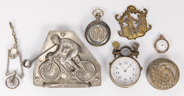 Radsport Antiquitäten  | Kleine Sammlung von Radsport - Antiquitäten: Taschenuhr von Andre Ligne Droite mit Radfahrermotiv auf dem Deckel; Uhrenkette mit Kompass und einem Fahradreifen; Meßinstrument von Lehmanns (Bienne); Klngelglocke von H.Bohlje, Emden mit Radfahrer Moitv; Plakette aus Messing mit Radfahrer, Messing Hohlprägung; defekte kleine Taschuhr mit Radfahrermotiv; profesionelle Schokaledengussform mit Rdasportmotiv. Alle Stücke aus der Zeit 1900-1920.