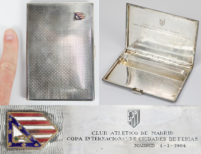 Madrid, Atletico Zigarettenetui 1964  | Zigarettenetui aus Silber mit aufgesetztem emaillierten Logo von Atletico Madrid. Innen mit Gravur "Club Atletico de Madrid. Copa Internacional de Ciudades de Ferias. Madrid 1 - I- 1964" (Messepokal, der Vorläufer des UEFA-Pokals) und einem graviertem Logo von Atletico. Silber(gepunzt mit dem spanischen Silberstern = 915er Silber + zweiten Stempel des Hersteller. Alle Punzen befinden sich auf der Unterseite der Halterung im Innenteil). Gewicht: 137 Gramm, 12x8,3x0,8 cm. Persönliches Stück des deutschen FIFA-Schiedsrichter Heinz Siebert (1925-2017) der von 1968 bis 1970 auf der FIFA-Liste stand. Er erhielt dieses Geschenk von Atletico Madrid anläßlich des Spiele im Messepokal am 1.1.1964 gegen Juventus Turin, bei dem Siebert als Linienrichter einegsetztz wurde.
