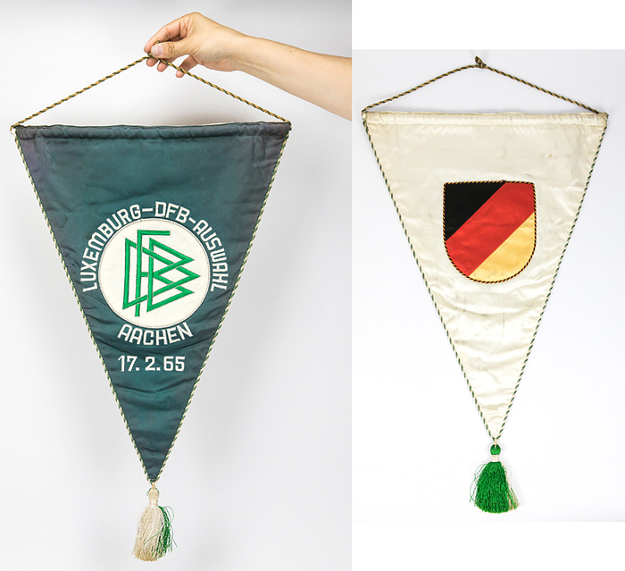  - Original DFB match pennant from the B-international match between Luxembourg and the DFB selection (0–6) on February 17, 1965, in Aachen. Green silk with embroidered grey lettering and an applied, embroidered DFB logo. Features a green-and-white silk border and a silk tassel. Dimensions: 50 x 37.5 cm (excluding tassel). --The captain of the Luxembourg team and the referees received this pennant. The pennant comes from the estate of a referee. Condition: B-