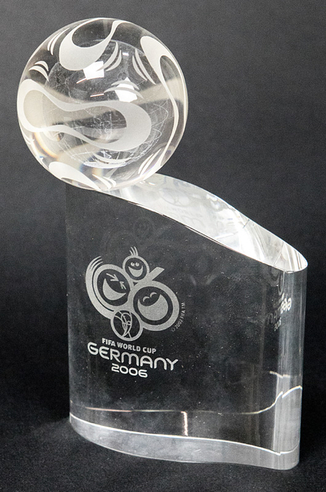  - World Cup 2006 Final : Glass sculpture with attached globe and the engraved logo of the 2006 World Cup in Germany. Also the engraved name of high person of the German football. Weight: 2 kg. Height: 24.5x18x7 cm. The guests of honour at the 2006 World Cup final in the Olympic Stadium Berlin on 9th July 2006  were each given a sculpute with their individual names as a souvenir. In original Box (Box with small signs of usage). Condition: A