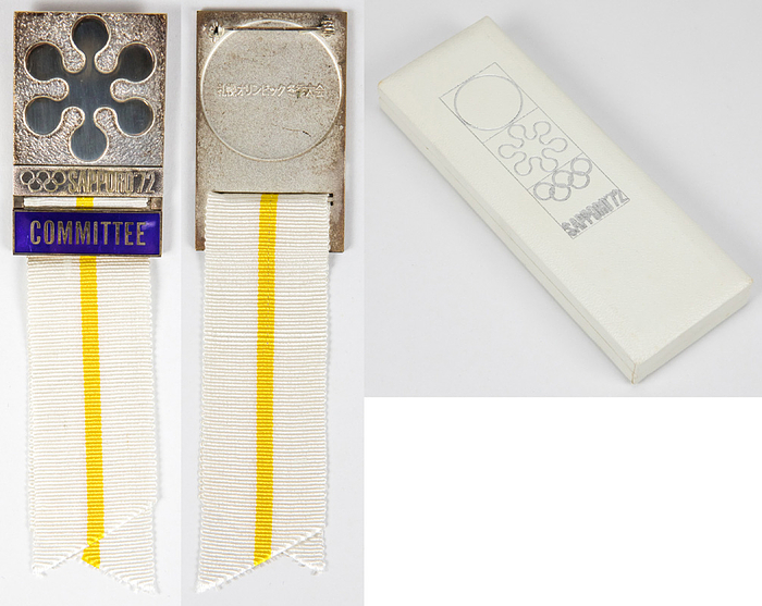  - Olympic Games Winter 1972: Official participation badge “Committee” (For members of the Winter Games organizing committee) for the Olympic Games Sapporo 1972. Silver-plated bronze. Writing border blue enamelled. With white silk ribbon with a yellow stripe, 14.5x3.8cm. In original Box  -From the collection of former IOC member Walter Tröger Condition: A-