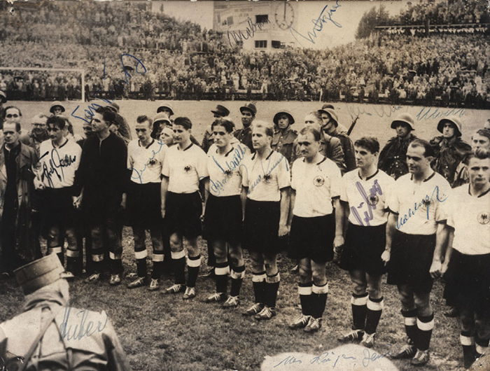  - B&W press photo (DPA) of the 1954 World Cup-winning German team at the awards ceremony following the final match against Hungary (3–2) on July 5, 1954, in Bern. Features 14 original signatures from the German players and the coach (F. Walter, Turek, Eckel, Liebrich, Schäfer, Mai, Schäfer, Kohlmeyer, Biesinger, Klodt, Metzner, Mebus, Huber [DFB official], and Deuser). 21 x 16.5 cm. --All signatures in ink, except for Schäfer's signature. Condition: A-