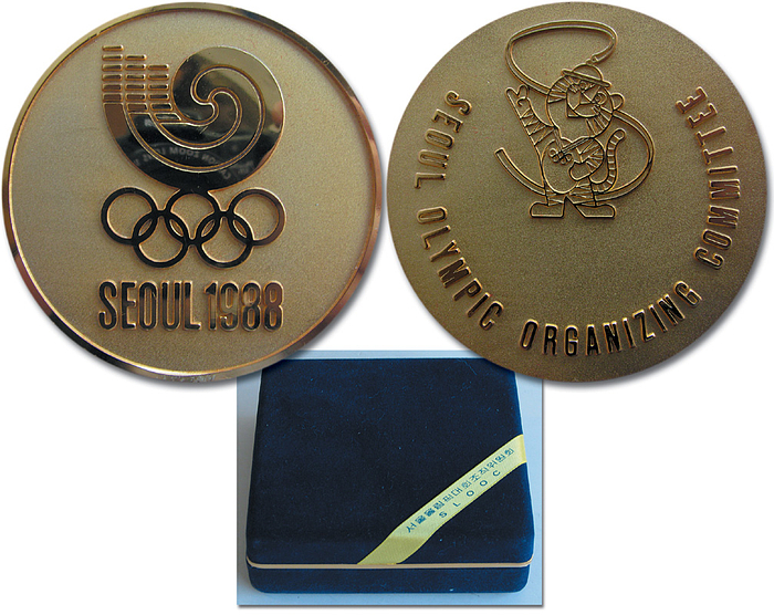  - Olympic Games 1988: "Seoul Olympic Orgaizing Committee Seoul 1988". Bronze, gold plated, size 7cm in original Box. Plus a visiting card from the OC President Tea Woo Roh. Issued only to guests of honour. Condition: A