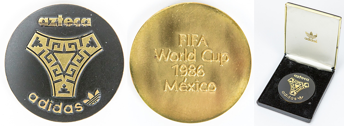 Erinnerungsmedaille WM86  | Erinnerungsmedaille der Firma „Adidas“ anläßlich der  Fußball - Weltmeisterschaft 1986. Vorderseite „Azteca Adidas“. Rückseite: „FIFA World Cup 1986 Mexico“. Bronze, vergoldet. 6,3 cm. In original Box.