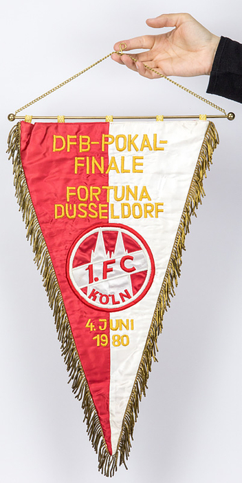 1)Köln,1.FC - Wimpel 1980  | Original Spielwimpel des 1.FC Köln aus Seide mit afgesticktem "DFB-Finale Fortuna Düsseldorf - 1.FC Köln 4.Juni 1980" (2:1).  Mit aufgesticktem Vereinsemblem. Goldbrokatfransen, Goldbrokatschlaufen. Messingstange mit Messingkgeln. 48x28 cm. Persönlicher Wimpel von Volker Roth, der als Linienrichter mitwirkte.