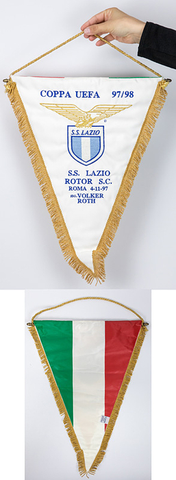 2Rom,Lazio - Spielwimpel 1997  | Original Spielwimpel  „Coppa UEFA 97/98. S.S. Lazio v Rotor S.C. Roma 4-11.1997 Sig. Volker Roth“ Rom v Wolgograd 3:0). Weißer Seidenwimpel mit aufgestickten Schriftzügen, Goldbrokatseidenfransen, Goldbrokatseidenkordel und Metallstange. Rückseite in den italienischen Landesfarben. Perönlicher Wimpel von Volker Roth (1942-2005, GER) anläßliche dieses UEFA Europapokalspieles. 45x33cm.