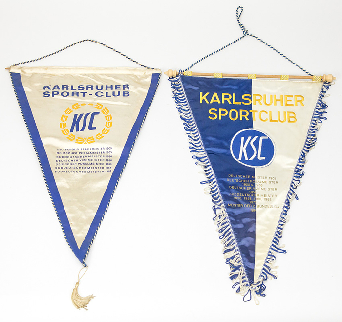 Karlsruher SC - Wimpel  |  Zwei Vereinswimpel Karlsruher SC: 1) Seidenwimpel, farbig bedruckt. Mit Seidenbordüre und Seidenbommel. Erfolge bis 1960 aufgedruckt, ca. 1968, 43x31 cm (Ohne Bommel). 2) Seidenwimpel bestickt und mit Aufdrucken der Erfolge des KSC "Meister der 2.Bundesliga 1984" letzter Eintrag. Seidenfrasnen, Goldbrokatschlaufen, Holzstange mit Kugeln, 45x31 cm (ohne Bommel)