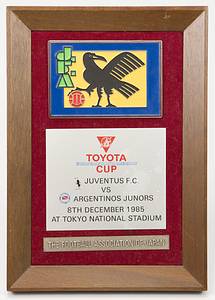  - Official commemorative plaque for the 1985 Intercontinental Cup, presented by the Japan Football Association; the plaque reads "Toyota Cup 1985 Juventus FC v Argentinos Juniors. 8th December 1985 at Tokyo National Stadium" (2–2; 4–2 on penalties). Features an applied, color-enamelled Japan Football Association emblem (10 x 7 cm). Mounted in a wooden frame (25.5 x 18 cm). Presented by the JFA to Volker Roth, the match referee. Includes: 6 private color photographs showing Volker Roth officiating the match alongside linesman S. Takada. Also includes two Japan Football Association pennants, each measuring 26 x 16 cm, bearing the original signature of Japanese referee S. Takada. Condition: A- - Bild 2