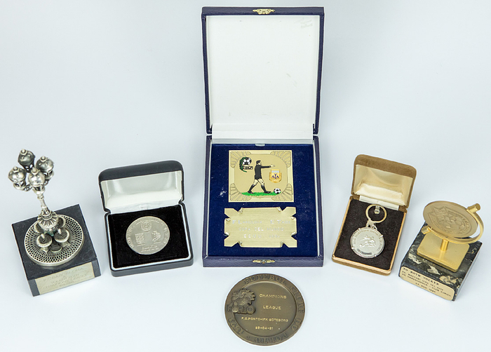 Turnier - Ehrengaben Volker Roth  | 6 verschiedene Ehrengaben anläßlich internatinaler Turniere aus der Sammlung von FIFA-Schiedsrichter Volker Roth: 1) FC Barcelona ChampionsLeague 10-5-2000, teilweise Silber, Marmorsockel, Höhe: 19,5 cm. 2) FC Porto: Medaille ChampionsLeague 21-04-1993 v IFK Göteborg. Bronze, 9 cm. 3) FC Maccabi Tel Aviv. Plakette auf Marmorsockel. Vs Grasshopper Zürich 23.08.1995. Bronze, vergoldet. Höhe: 14 cm. 4) Fußball Weltmeisterschaft 1982. Schlüsselanhänger des spanischen Fußballverbandes mit Namensgravur "V.Roth. Silber, 3,5 cm. 5) Erinnerungsplakette des argentinsichen Fußballverbandes für Schiedsrichter anläßlich der Fußball - Weltmeisterschaft 1994, Metall, vergoldet, farbig emailliert, 17x13 cm. 6) Fußballverband Mexiko. Teilnehmermedaille  "Torneo Azteka 2000" Dreiländerturnier im Juni 1985 mit den Team von Deutschland, England und Mexiko. Bronze, versilbert, 5 cm.