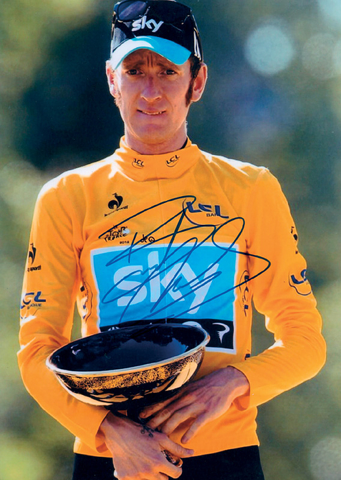  - Large photograph of Bradley Wiggins (GBR), 2012 Tour de France winner, featuring an original signature. Wiggins is also a five-time Olympic cycling champion (2000–2016), and has additionally won one silver and two bronze medals. He is a seven-time world champion. Dimensions: 30 x 21 cm. Includes a COA from "eBay Sales at Autograph Collectables." Condition: A