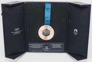 Siegermedaille 2024  | Bronzemedaille der Olympischen Spielen Paris 2024 für den 3.Platz im Taekwondo für einen amerikanischen (Süd - Mittel) Athleten mit der Aufschrift "Jeux de La XXXIIIe Olympiade Paris 2024". Kupferlegierung auf der Rückseite in der Mitte ein originalsechseckiges Stück Eisen aus dem Eiffelturm, das bei Renovierungsarbeiten entnommen wurde mit dem Symbol der Olympiade und der Inschrift "Paris 2024". Gewicht ca. 325 Gramm, 8,5 cm mit original Seidenband. In original Lederschatulle, ein dreifach klappbares (Triptychon-) Etui aus strukturiertem, violettem (blau/lila) Leder mit goldenen Olympischen Ringen und dem Paris-2024-Logo. Innen ausgeschlagen mit Verloursleder. Aufgesetzte Plakette für offiziellen IOC - Siegerpin für Bronzemedaillengewinner. 28x22x9 cm. Dabei zwei Echtheitszertifikate von Paris Mint!. - Bild 4