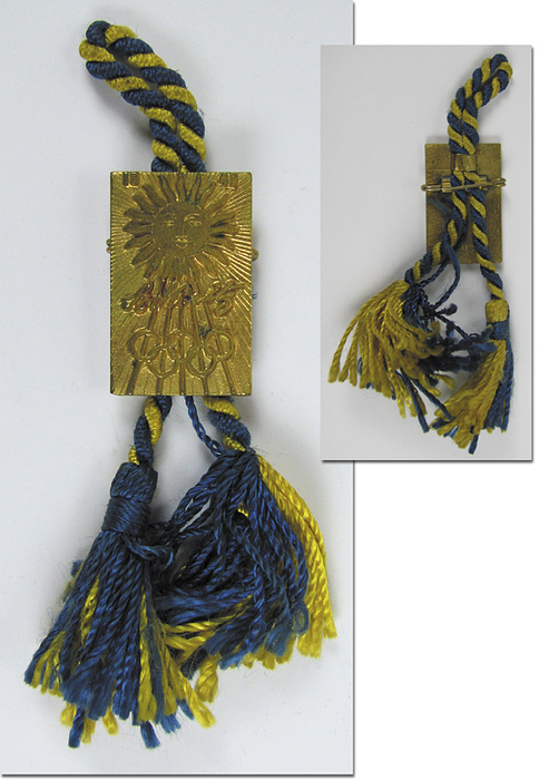 Offizielles Besucherabzeichen der Olympischen Winterspiele St.Moritz 1948. Bronze, vergoldet mit blau-gelber Kordel. Hersteller: Huegenin; 2,8x1,8 cm.