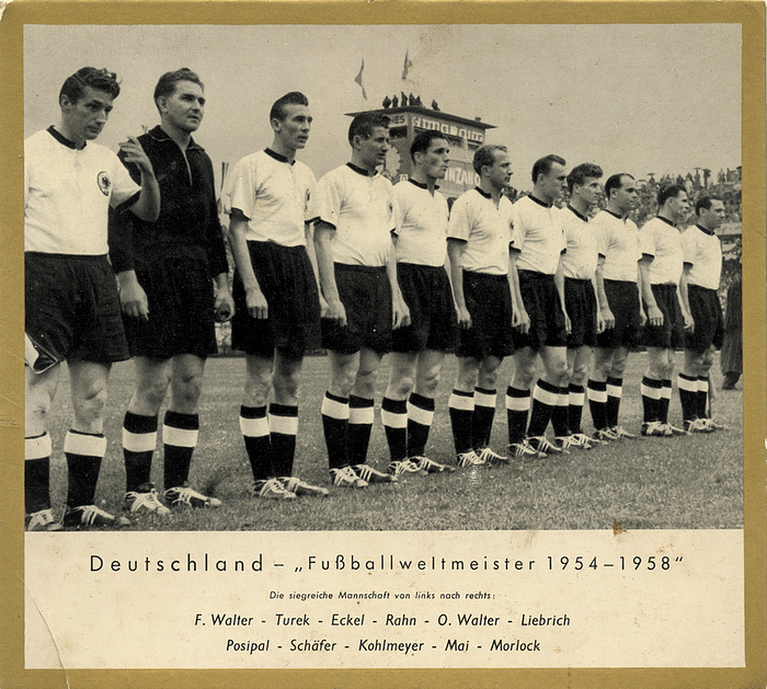 IMOGLAS WM 1954  | „Deutschland - Fußballweltmeister 1954-1958“ Papprahmen zum aufhängen mit Kunststoffbeschichtung der Firma „Imoglas“. s/w-Foto mit Goldrand, 1954. 18,5x16,5 cm.