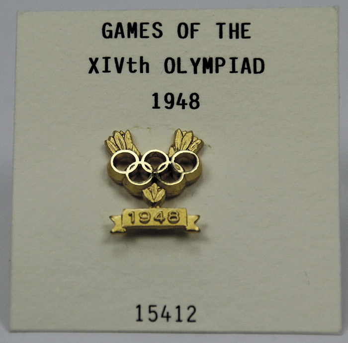Offizielles Siegerabzeichen des IOC für die Olympischen Spiele London 1948" mit der Nummer "15412" für eine Goldmedaille. Bronze, verdoldet mit Rückseitig eingravierter Nummer "15412". Hersteller: Bertoni, Mailand. 2x1 cm In Originaletui.