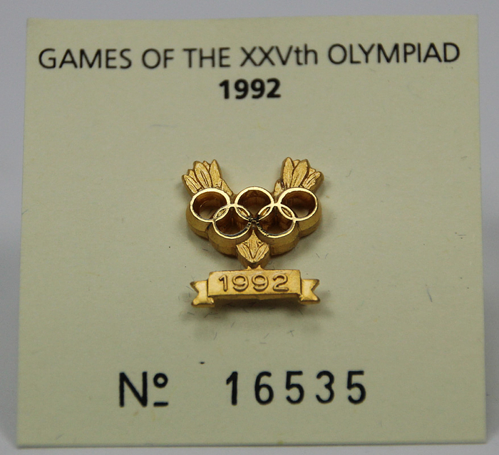 Olympic Games 1992. IOC Pin for Gold medalists - Commemorative IOC pin for a gold medallist in the Olympic Games in Barcelona 1992. Personal numbered pin which a German fencer received for winning  the first place. Numbered "16535" (Number can also be found on rear of the pin). Gilt bronze, 1.5 x 1.3 cm. In original case. Condition: A