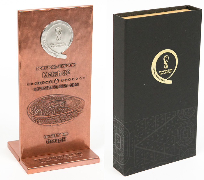 Offizielle Spielplakette von der Fußball - Weltmeisterschaft 2022 in Quatar vom Vorrundenmatch Portugal v Uruguay mit der Aufschrift "Portugal - Uruguay Match 32. November 28, 2022 . 10 PM. Lusail  Stadium Group H" mit Sockel (7,5x7,5 cm) mit der Aufschrift "FIFA World Cup Quatar 2022". Kupfer mit aufgesetztem WM Logo, 15x7,5 cm In original Box.
