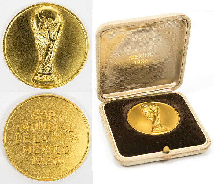 Teilnehmermedaille WM1986 Gold  | Goldene Teilnehmermedaille „Copa Mundial de la FIFA Mexico 1986“. Hersteller:  Huguenin. Gold (gepunzt 585; Gesamtgewicht 72 Gramm; Goldwert am 27.4.25 ca. 3800,. €), 5 cm. In original Etui.