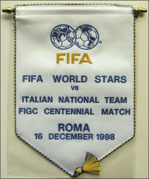 FIFA-Wimpel 1998  | Offizieller Spielwimpel der FIFA für das Spiel der "FIFA World Stars vs Italian National team FIGC Centennial Match, Roma 16 December 1998". Seidenwimpel, farbig bestickt mit drei Seidenbommeln und Messingstange mit Messingkugeln. In original Plastikhülle. 27x22 cm.