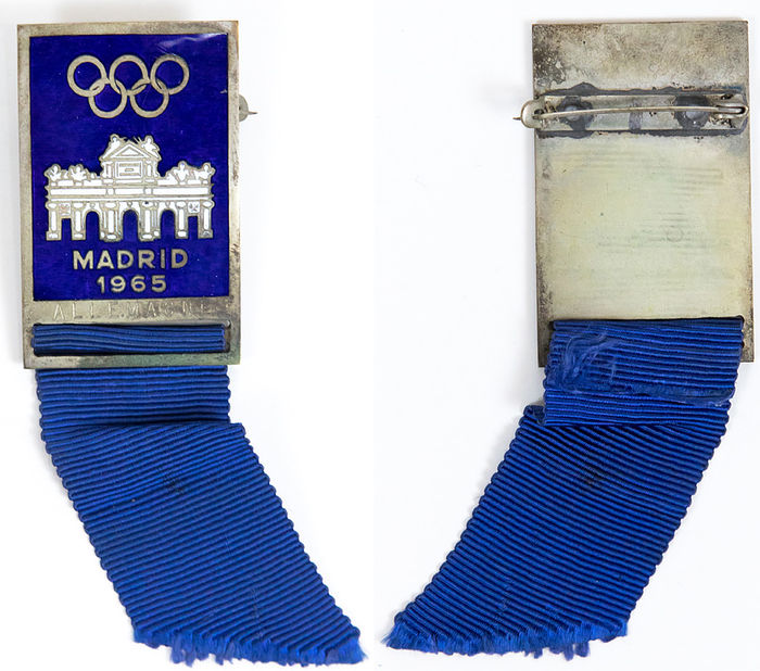 IOC-Session 1965  | Teilnehmer-Abzeichen der 65. IOC-Session "Madrid 1965" mit der Gravur "Allemagne". Bronze, versilbert, blau.weiß emailliert, mit blauem Seidenband, 10,5 x3,2 cm.