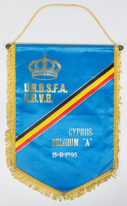 Football Match Pennant 1995  Belgium - Zypern - Original match pennant of the Belgian national team for the Cyprus vs. Belgium international match with the gold imprint "Cyprus - Belgium "A" 14 - 11 - 1995." Blue silk pennant with gold silk fringes, silk cord, and plastic pole. 38 x 27 cm. --This pennant was presented to Cyprus, the referees, and the UEFA observers. The pennant comes from the collection of an official of the Belgian Football Association. Condition: B