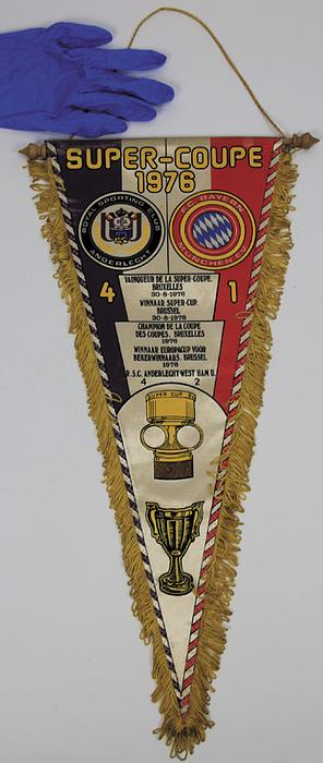 Souvenirwimpel "Super - Coupe 1976 RSC Anderlecht v Bayern München 1976". Farbig bedruckter Seidenwimpel aus dem Jahr 1976. Mit Seidenfransen, Holzstange und - kugeln, 52x23 cm.