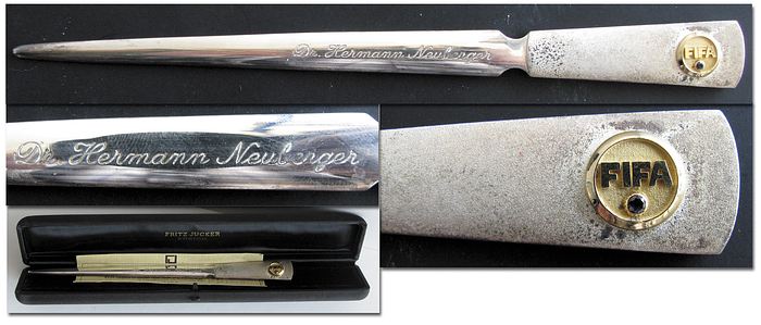 Silver FIFA Letter Opener approx. 1974 - With mounted FIFA logo in gold with diamond insert, engraved "Dr.Hermann Neuberger". Opener in 925 stamped silver (50 grammes), FIFA Logo stamped 750  gold with an inlaid blue sapphire. Size 17.5cm. In original presentation case. Exlusive unique present mad to the German FA President appr. 1974! With certificate of authenticity from "F.Jucker, Zurich". --slightly tarnished Condition: A
