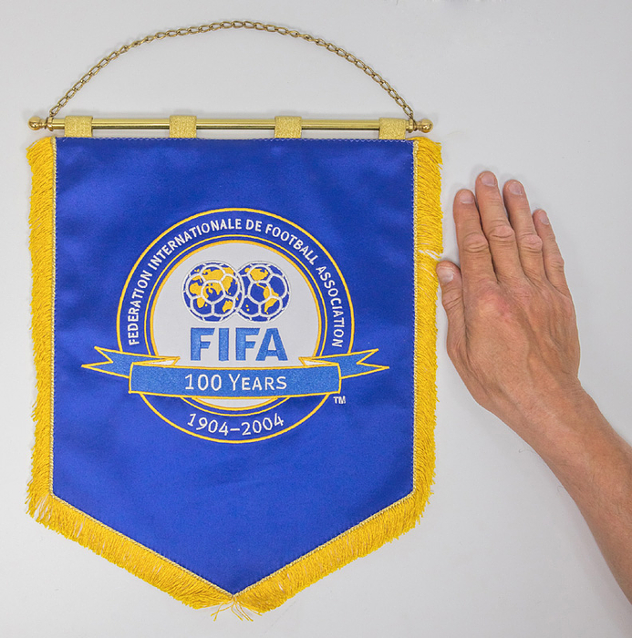 FIFA-Wimpel 1904-2004  | Großer, offizieller Jubiläumswimpel der FIFA "FIFA 1904-2004 - 100 Years". Seidenwimpel, farbig bestickt mit Seidenfransen, vier Goldbrokatschlaufen und vergoldeter Messingstange mit Messingkugeln, 37x29 cm.