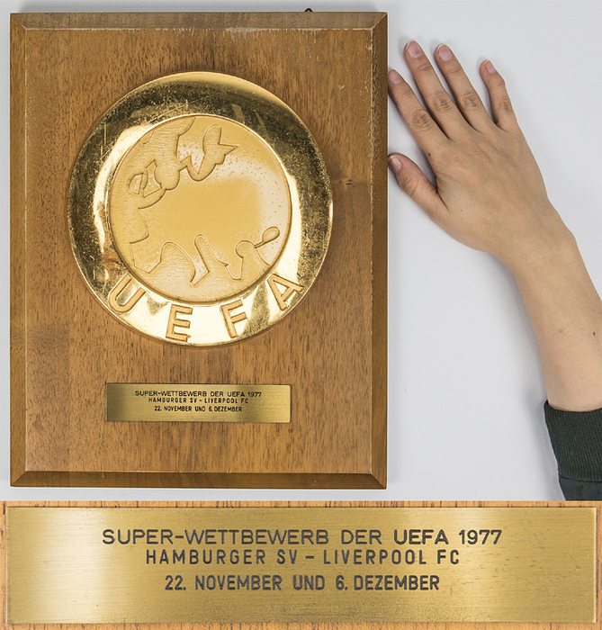 Offizielle Ehrenplakette der UEFA für den DFB anlässlich des Europapokalendspieles Landesmeister und Pokalsieger 1977 - Supercup. Große, vergoldete UEFA Logoplakette (20 cm) aufmontiert auf Holzplatte. Mit aufgesetzter gravierter Messingplakette mit der Inschrift "Super-Wettbewerb der UEFA 1977 Hamburger SV - Liverpool FC 22.November und 6.Dezember" (1:1 + 0:6). Hersteller: Huegenin, Susse. 35x28 cm. Museumstück!.