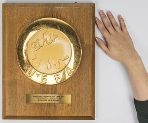 Offizielle Ehrenplakette der UEFA für den DFB anlässlich des Europapokalendspieles Landesmeister und Pokalsieger 1977 - Supercup. Große, vergoldete UEFA Logoplakette (20 cm) aufmontiert auf Holzplatte. Mit aufgesetzter gravierter Messingplakette mit der Inschrift "Super-Wettbewerb der UEFA 1977 Hamburger SV - Liverpool FC 22.November und 6.Dezember" (1:1 + 0:6). Hersteller: Huegenin, Susse. 35x28 cm. Museumstück!. - Bild 2