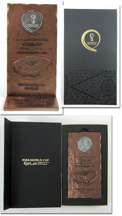 Offizielle Spielplakette von der Fußball - Weltmeisterschaft 2022 in Quatar vom Vorrundenmatch Korea v Ghana mit der Aufschrift "Korea Republic - Ghana Match 30. November 28, 2022 . 4 PM. Education City Stadium Group H" mit Sockel (7,5x7,5 cm) mit der Aufschrift "FIFA World Cup Quatar 2022". Kupfer mit aufgesetztem WM Logo aus Silber, 15x7,5 cm In original Box.