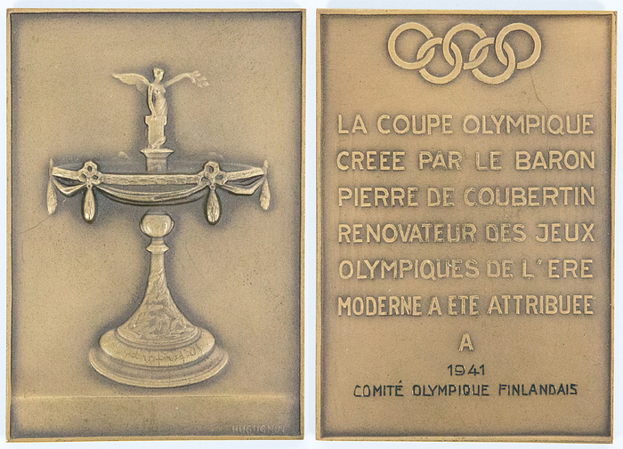 Bronze Plakette für die Teilnehmer an der Verleihung des Olympischen Pokals an das Olympische Komitee von Finland 1941 durch das IOC. Vorderseite: Relief des Olympischen Pokals. Rückseite: Olympische Ringe mit Schriftzug "La Coupe Olympique creee par le Baron de Coubertin renovateur des Jeux Olympiques de l´ere moderne a ete attribuee a 1941 Comité Olympique Finlandais". Bronze, 7,3x5,2 cm (102 Gramm). Hersteller: "Huguenin".