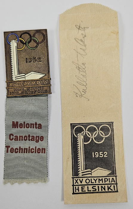 Teilnehmerabzeichen „Melonta. Canotage Technicien“ (Kanu Techniker) für die Olympischen Spiele Helsinki 1952. Bronze, mehrfarbig emailliert. Mit hellblauen bedrucktem Seidenband, 11,5x3,3 cm. mit original Papiertüte für dieses Abzeichen.