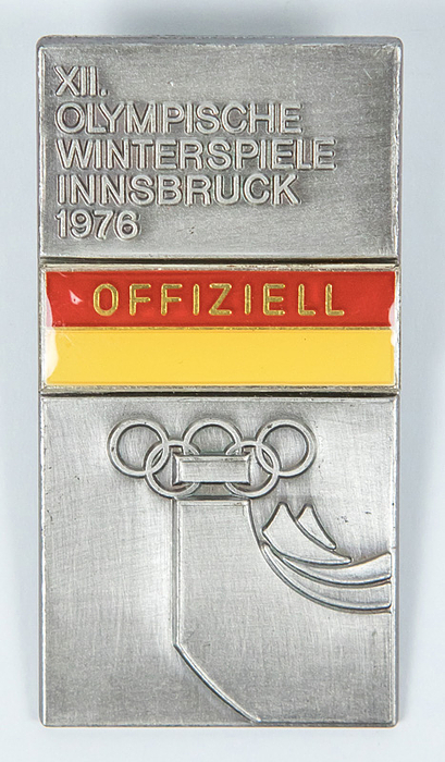 „Offiziell. XII. Olympische Winterspiele Innsbruck 1976“. Edelstahl, zweifarbig emailliert. 5,8x3cm.
