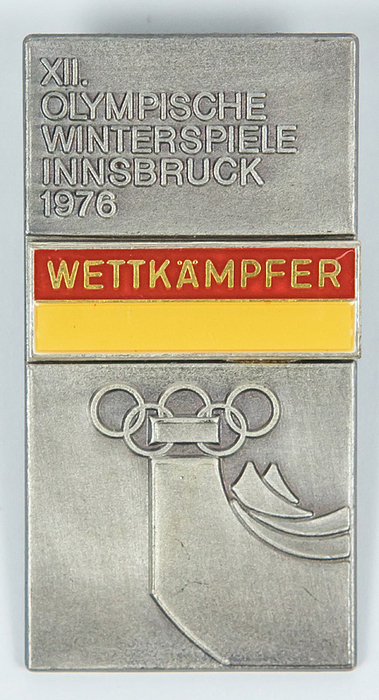"XII. Olympische Winterspiele Innsbruck 1976. Wettkämpfer“. Offizielles Teilnehmerabzeichen für Athleten. Edelstahl, zweifarbig emailliert. 5,8x3 cm.