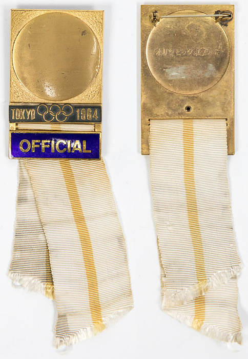Offizielles Teilnehmerabzeichen Olympische Spiele Tokyo 1964 „Official“. Bronze, vergoldet. Schriftleiste blau emailliert. Weiß-gelben Seidenband. 14x3,8cm.