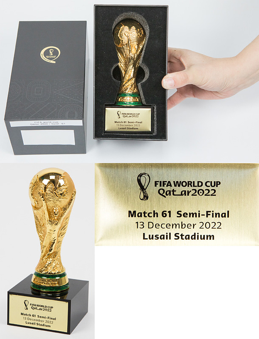 FIFA Weltpokal. Vergoldeter Tombakpokal auf schwarzem Sockel, dieser mit Metallschild mit WM 2022 Logo und Inschrift „FIFA World Cup Quatar 2022. Match 61 Semi-Final 13 December 2022 Lusial Stadium“ (Argentinien v Kroatien 3:0). Höhe 15 cm. In original Verpackung.
