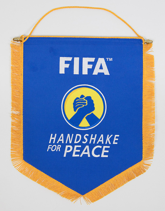 Farbig bestickter FIFA-Seidenwimpel "Handshake for Peace" mit gelber Seidenfransen und Metallstange ca. 2012. 38x32 cm.