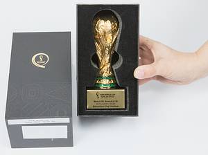 FIFA Weltpokal. Vergoldeter Tombakpokal auf schwarzem Sockel, dieser mit Metallschild mit WM 2022 Logo und Inschrift „FIFA World Cup Quatar 2022. Match 55 Round of 16 6 December 2022 Education City Stadium“ (Marokko v Spanien 0:0). Höhe 15 cm. In original Verpackung. - Bild 2