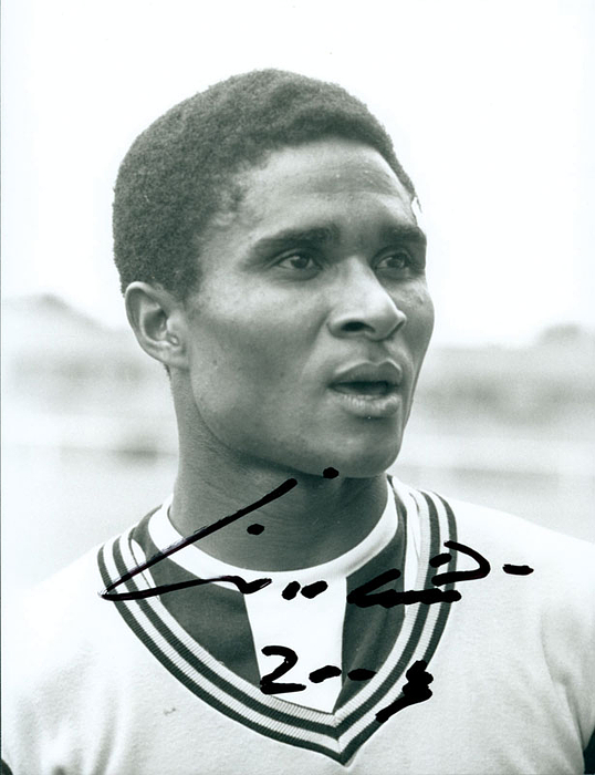 (1942-2014) s/w-Pressefoto mit Originalsignatur von  Eusebio im Trikot von Benfica Lissabon. Portugiesischer  WM-Torschützenkönig 1966 und Europas Fußballer des Jahres 1965. 22x16,5 cm.