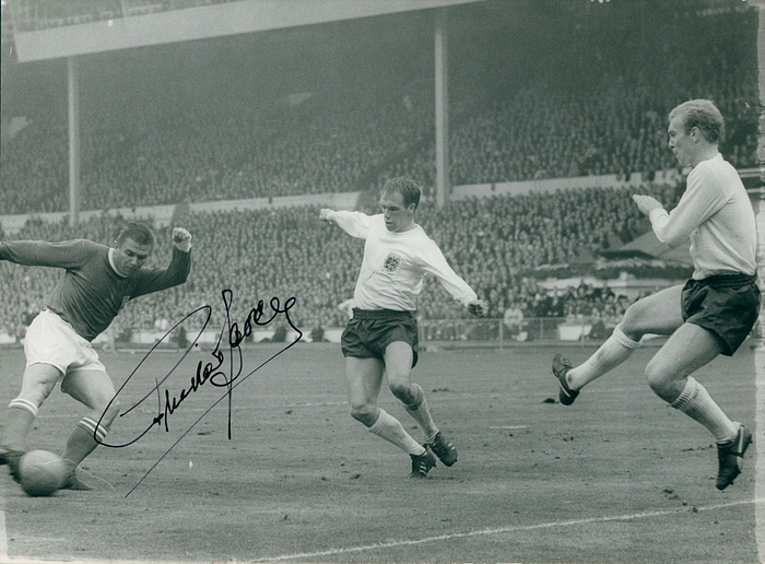 (1927-2006) S/W-Pressefoto (Horst Müller) mit Originalsignatur von Ferenc Puskas (82 Länderspiele und 84 Tore, Vize-Weltmeister 1954 mit Ungarn, Real Madrid). Puskas im Trikot der FIFA Weltauswahl im Spiel 1963 England v Rest of the World (1:2) in London. 24,5x17,5 cm.