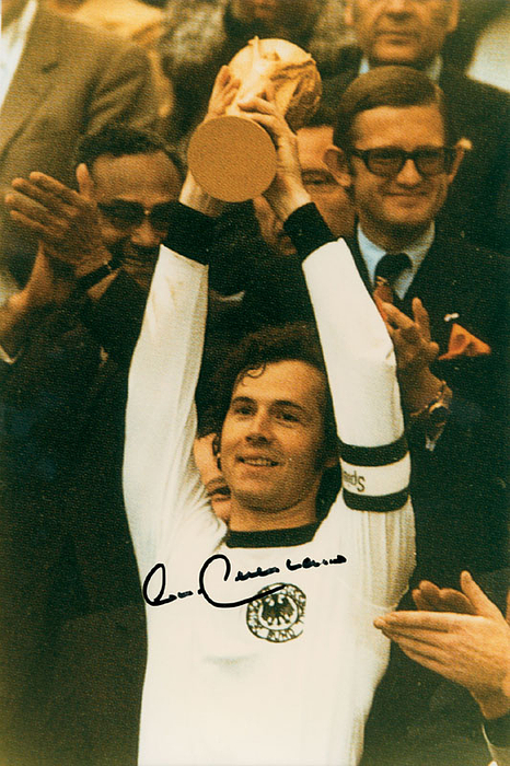 (1945-2024) Großes Farb-Reprofoto mit Originalsignatur von Franz Beckenbauer. Das Foto zeigt den "Kaiser" bei der Siegerehrung der Fußball-Weltmeister 1974. 30,5x20,5 cm.